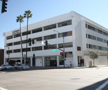 A white building with palm trees in front of it.